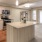 Large well lit kitchen with island and stainless steel apliances adjacent to the living room