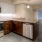 Large well lit kitchen with dark wood cabinets and stainless steel appliances adjacent to the living room