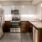 Large well lit kitchen with dark wood cabinets and stainless steel appliances adjacent to the living room