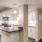 Spacious well lit kitchen with an island and whit cabinets